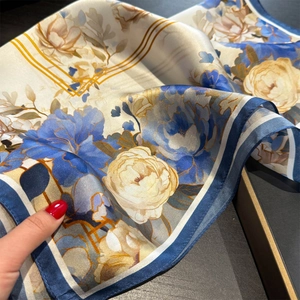 Close-up of silk scarf showing detailed floral patterns and smooth satin texture