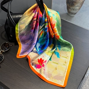 Carré de soie élégant à motif floral drapé sur un sac en cuir noir avec lunettes