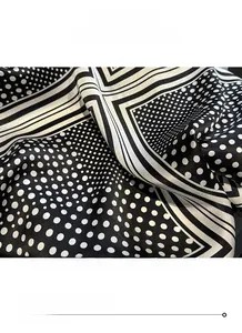 Close-up of fine stitching and hem detail on a polka dot silk square scarf