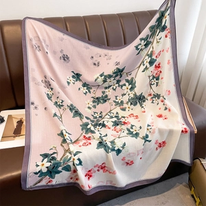 Large floral silk scarf with pink gradient and magnolia print draped on a leather sofa