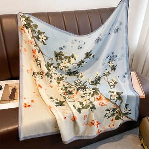 Large vintage square scarf with light blue floral print draped on a leather sofa