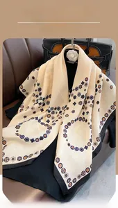 Detailed close-up of beige vintage floral silk scarf with black borders on leather sofa