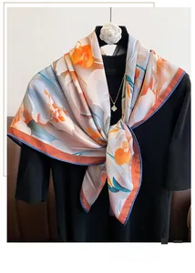Detailed close-up of blue and orange floral print on a silky scarf with fine blue piping