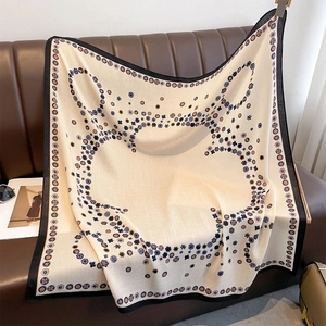 Elegant beige double-sided scarf with floral patterns on a leather sofa