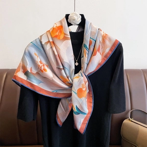Elegant oversized floral scarf with orange and blue abstract print on a display stand