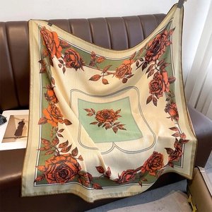 Floral print square scarf with orange roses and green border on leather background