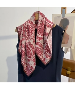 Détail d'un foulard en soie à motif damassé rouge avec ourlet brun sur tissu beige