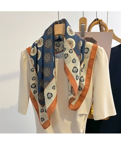 Gros plan d'un foulard en soie à fleurs de camélia avec des bordures caramel