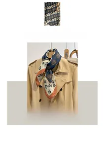 Détails de l'écharpe en coton bleu marine à fleurs portée avec un trench-coat beige