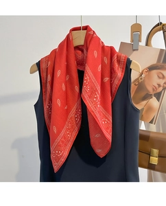 Detail of red paisley square scarf with white prints hanging on a wooden hanger