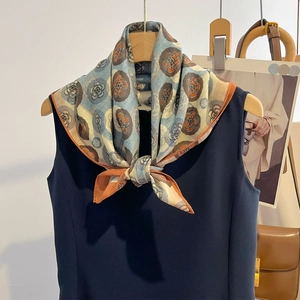 Foulard en soie à motif camélia à pois avec bords rouges roulés sur un cintre en bois