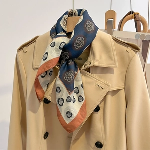 Foulard rétro en soie à pois et camélia porté sur un trench-coat kaki pour un look élégant