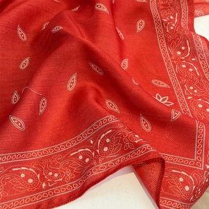Macro view of red paisley pattern silk scarf showing detailed twill texture and soft folds