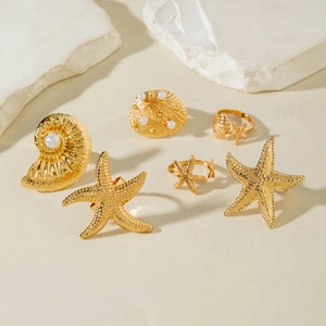 Detail of gold starfish and shell ring set with textured finish and pearl accents