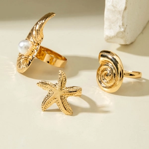 Detailed shot of ocean-themed gold ring set with starfish, shell, and pearl elements