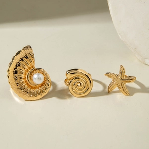 Detailed shot of golden sea star and seashell rings set featuring white pearls