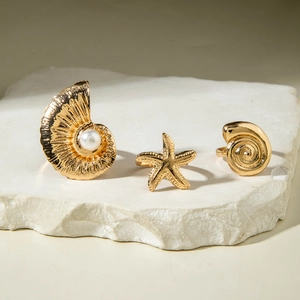 Detail of three gold ocean-themed rings with pearl-inlaid shell and starfish designs