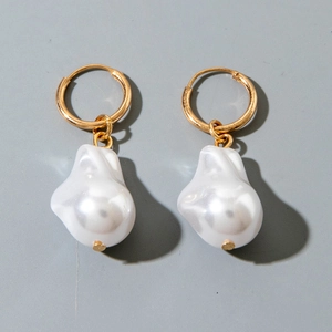 Detailed view of gold hoop earrings with irregular baroque pearls on grey background