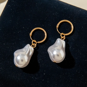 Close-up of gold hoop earrings with irregular baroque pearls on black velvet