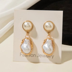 Close-up of baroque pearl earrings with gold-plated metal frames on a display card