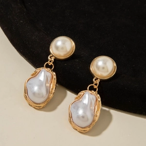 Macro detail of Baroque pearl drop earrings featuring textured gold-plated metal frames