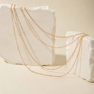 Minimalist multi-layer gold link chains displayed on decorative white stones