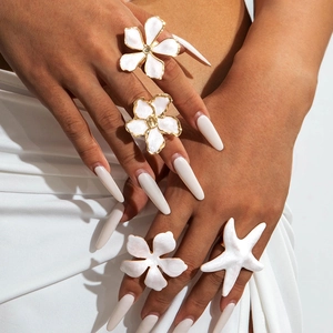 Détail de bagues fleurs en émail blanc et bague étoile de mer portées par un mannequin