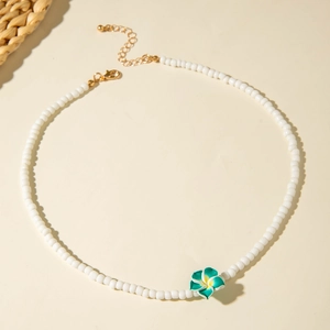 Detail of bohemian beaded necklace with white resin flower charm and gold lobster clasp