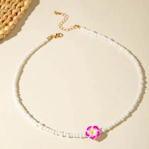 Detail of beaded necklace with pink plumeria flower pendant and gold lobster clasp