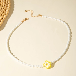Detail of bohemian handmade beaded necklace with white pearls and yellow plumeria flower
