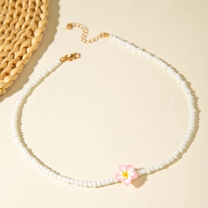 Close-up of beaded necklace with pink plumeria pendant and adjustable gold clasp
