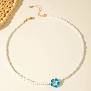Close-up of white beaded summer necklace with a blue gradient resin frangipani flower