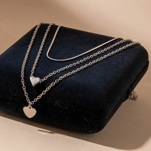 Three-layer silver necklace with heart pendants and layered snake chain on velvet
