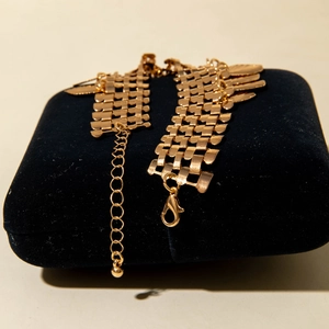 Close-up of golden braided metal bracelet texture with lobster clasp and extension chain