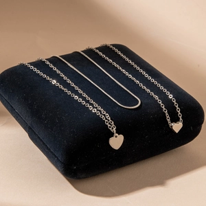 Detailed shot of triple-layer silver necklaces with heart pendant on black velvet