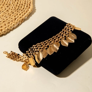 Detail of bohemian gold leaf anklet with fringed leaf charms on black velvet pad