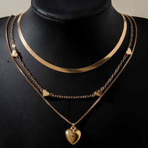 Close-up of golden multi-layered necklace set featuring heart pendants on a black neck model