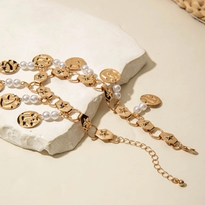 Detail of gold chain anklet featuring engraved star links, white pearls and hammered pendants