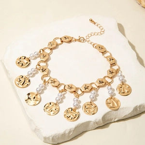 Detail of gold layered anklet with star hexagon links, pearls and textured pendants