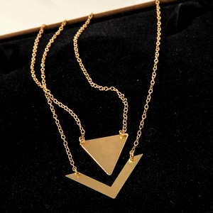 Detail of layered gold geometric necklace with solid triangle and V-shaped pendants