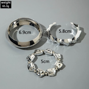 Détail de bracelets perlés argentés et joncs épais texturés effet lave métallique