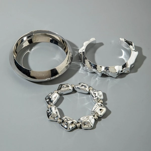 Détail d'un ensemble de trois bracelets en métal argenté avec perles et anneau lisse poli