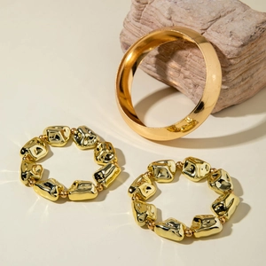 Détail d'un ensemble de trois bracelets dorés à perles métalliques sur base de pierre