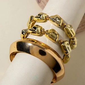 Détail d'un bracelet jonc doré large et de bracelets à perles irrégulières