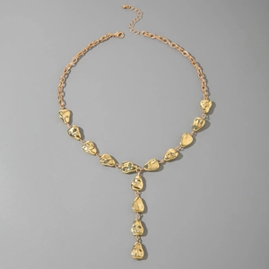 Golden Y-shaped necklace with irregular lava-style organic metal charms on grey background