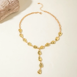 Detail of gold Y-shaped necklace featuring textured teardrop charms on a minimal background