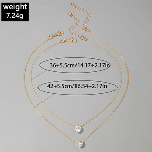 Detail view of a gold double-layer necklace with round and heart zirconia pendants