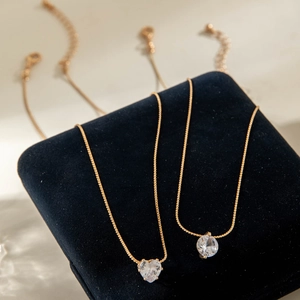 Elegant gold layered necklaces with heart and round crystal pendants on blue velvet