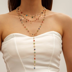 Detail of layered gold Y-necklace with multi-colored heart and star crystal pendants