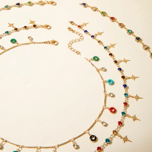 Detailed view of layered gold necklaces with colorful crystals and star pendants